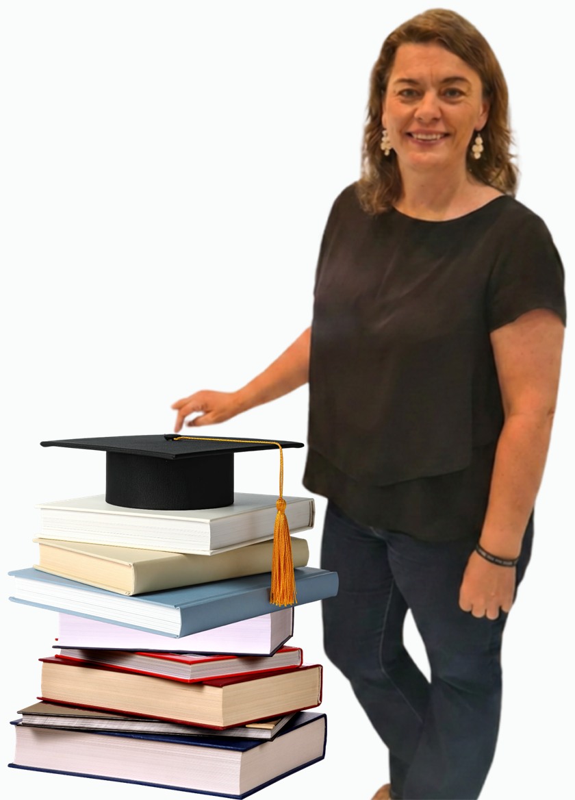Dr Mariette Frazer standing beside a stack of books topped with a graduation cap